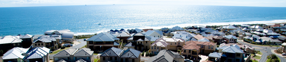 Aerial view of coastal residential neighborhood with houses overlooking blue ocean and beach